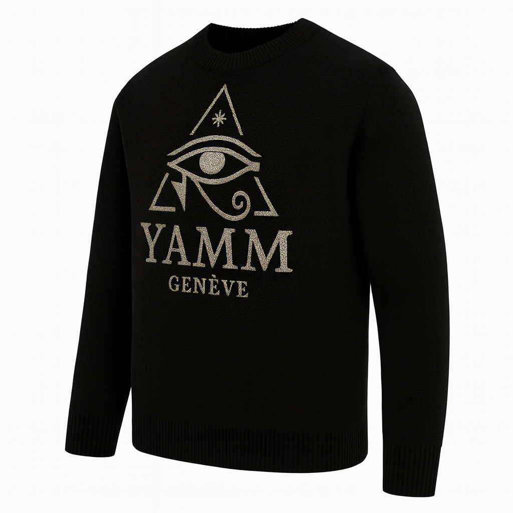 Le Pull Œil Suprême YAMM se dévoile dans une vue pivotée trois-quarts, révélant la profondeur du tissu noir et l’éclat subtil de la broderie dorée. L’angle met en valeur la coupe structurée, les finitions bords-côtes et la silhouette équilibrée du vêtement. L’emblème sacré — l’Œil d’Horus dans son triangle doré — capte la lumière avec intensité, soulignant le caractère mystique et raffiné de la pièce. La broderie YAMM Genève renforce la signature artisanale de la Maison, symbole d’excellence et d’élégance contemporaine.